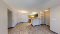 This single-floor residence offers a functional and comfortable layout with a clean, neutral aesthetic throughout. The open-concept living and dining area is anchored by wood-look plank flooring and ceiling fans, creating a bright and airy atmosphere. Natural light filters in through windows, and a hallway connects the main living space to the private quarters of the unit.

The kitchen is positioned adjacent to the living area and features warm-toned wood cabinetry, light countertops, a gas range, and ample upper and lower cabinet storage. A peninsula counter separates the kitchen from the living space, providing additional prep and dining space. A built-in shelving unit nearby adds convenient storage.

The bedrooms are well-proportioned, each equipped with ceiling fans and windows that allow natural light and outdoor views. The neutral gray walls and wood-look flooring carry throughout, maintaining a cohesive look.

Two full bathrooms serve the unit, each featuring a single-sink vanity with wood cabinetry and dark countertops, a tub-shower combination, and wood-look flooring. The design is practical and consistent throughout.

Overall, the space presents a straightforward, functional layout with consistent finishes, making it a comfortable and easy-to-maintain living environment.