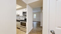 This single-floor residence offers a thoughtfully designed layout with modern finishes throughout. The kitchen is a standout feature, showcasing white cabinetry, granite countertops, a mosaic tile backsplash, and a full suite of stainless steel appliances including a range, over-the-range microwave, dishwasher, and refrigerator. A peninsula provides additional counter space and serves as a natural transition into the adjoining living areas, all finished with durable wood-style flooring.

The living room is bright and welcoming, featuring a tile-surround fireplace as a focal point, complemented by wood-style flooring and a window that brings in natural light. A separate room opens to the outdoors through a sliding glass door, offering views of a lush, green landscape and seamlessly connecting indoor and outdoor living.

The bedroom features plush carpeting and a window for natural light, creating a comfortable and restful environment. Two well-appointed bathrooms are finished with large-format tile flooring, white vanity cabinetry, granite countertops, and modern hardware — one with a tub/shower combo and one with a walk-in glass-door shower. A dedicated utility area with laundry hookups adds everyday convenience to this clean and move-in ready space.