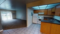 Located at 1014 W Irving Park Rd in Bensenville, IL, this single-floor unit offers a practical and straightforward layout designed for comfortable everyday living. The kitchen is well-equipped with warm oak cabinetry providing ample storage, dark countertops, a white electric range, a full-size refrigerator, and a stainless steel sink. A drop ceiling with recessed lighting brightens the space. The kitchen opens toward the dining and living areas, which feature a combination of tile and carpet flooring. The living area is generously sized, finished with wall-to-wall carpet, a baseboard heating system, and a wall-mounted air conditioning unit. A sliding glass door allows natural light to flow in and provides access to the outdoors. A small chandelier marks the transition between the dining and living spaces, adding a touch of character. The bedrooms are carpeted and offer a quiet, comfortable retreat, with one featuring a dedicated closet with rod and shelf storage and direct access to the bathroom. The full bathroom includes a tiled tub and shower combination, a single-sink vanity with cabinet storage below, a mirror medicine cabinet, and tile flooring. Throughout the unit, baseboard heaters provide consistent warmth, and the overall layout is efficient and easy to navigate.