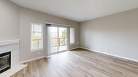 This one-bedroom, one-bathroom unit in Redmond, WA offers a well-designed layout that maximizes its comfortable footprint. The open-concept living area features light-toned hardwood-style flooring, neutral walls, and a marble-surround fireplace as a central focal point. A sliding glass door opens to a private balcony, flooding the space with natural light and offering views of the surrounding neighborhood.

The kitchen is thoughtfully appointed with white shaker-style cabinetry, a hexagonal tile backsplash, quartz countertops with an undermount sink, and a full suite of stainless steel appliances including a refrigerator, range, and microwave. Pendant lighting above the curved peninsula adds a modern touch.

The bedroom features plush carpeting, a bay-style window arrangement that brings in ample natural light, and access to a dedicated closet. A second carpeted room provides additional flexible space. The bathroom includes a full tub/shower combination with brushed nickel fixtures.

Additional highlights include in-unit laundry, recessed lighting, and a clean, contemporary aesthetic throughout. The unit is located on the second floor within a well-maintained Redmond community.