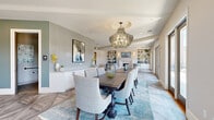 Located in the heart of Alpharetta, GA, this refined single-floor space on Commerce Street offers a thoughtfully designed open-concept layout that seamlessly connects the dining, kitchen, and living areas. The dining room makes a striking impression with its intricate herringbone-patterned flooring, a statement chandelier, textured accent wall, and a large dining table ideal for gatherings. Floor-to-ceiling French doors flood the space with natural light and open directly onto a generous outdoor terrace, where panoramic views of the Alpharetta skyline and lush treetops create an inviting backdrop. The kitchen is outfitted with crisp white cabinetry, granite countertops, a chevron-tile backsplash, stainless steel appliances, and a built-in wine cooler, combining style with functionality. The living room offers a warm, intimate atmosphere anchored by a classic fireplace, built-in shelving with geometric display niches, and soft, neutral tones throughout. Two well-appointed bathrooms feature bold subway tile accent walls with decorative mosaic borders, granite vanities, and modern matte black fixtures. The overall ambiance is polished and contemporary, with a cohesive palette of soft blues, warm neutrals, and natural stone textures lending the space an elevated yet welcoming character.