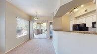 This single-floor residence offers a thoughtfully designed layout that balances comfort and functionality. The open-concept living and dining area is finished with neutral-toned carpet and bathed in natural light through large windows fitted with horizontal blinds. A ceiling fan with a light fixture keeps the space comfortable, while a sliding glass door leads directly to an outdoor balcony, offering views of surrounding greenery. The kitchen is well-equipped, featuring white cabinetry, granite-style countertops, wood-look flooring, and a full suite of black appliances including a refrigerator, range, microwave, and dishwasher. A raised breakfast bar provides a convenient transition between the kitchen and living area. The bedrooms are carpeted and generously sized, each with ceiling fans, natural light from windows, and ample wall space. One bedroom features a sliding glass door access to the balcony. The bathroom includes a white vanity with granite-style countertops, a large mirror, and wood-look flooring. A dedicated laundry room houses a full-size washer and dryer alongside a water heater, adding practical everyday convenience. Overall, the space presents a clean, neutral palette with consistent finishes throughout.