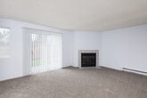 This single-floor residence offers a well-organized layout with a comfortable, functional design throughout. The living room is a standout space, featuring plush wall-to-wall carpeting, a classic tile-surround fireplace, and a sliding glass door with vertical blinds that opens to an outdoor view, allowing natural light to fill the room. An additional window further brightens the space, and a baseboard heating system ensures year-round comfort.

Adjacent to the living room, a dedicated dining area is complemented by a ceiling fan and additional windows that provide ample natural light. The kitchen is efficiently designed with light wood flooring, white cabinetry, a stainless steel refrigerator, a dishwasher, and a double-basin sink — offering practical workspace for everyday use.

The bedrooms are carpeted and feature baseboard heating and windows with blinds. The textured ceilings are consistent throughout the living spaces, lending a classic character to the interior.

The bathrooms include a full bath with a soaking tub, smooth surround walls, and wood-look flooring, as well as a smaller half bath equipped with a vanity, mirror, and wood-look flooring. The overall palette of neutral whites and light grays creates a clean, move-in ready atmosphere throughout the space.