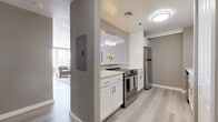 Located in Hartford, CT, this thoughtfully updated single-floor residence combines modern finishes with a functional, well-organized layout. The kitchen is a standout feature, showcasing white shaker cabinetry, light quartz countertops, stainless steel appliances including a range and refrigerator, and light wood-style flooring that extends throughout the common areas. A pass-through window connects the kitchen to the living space, enhancing the open feel. The living area is bathed in natural light through a wide bank of windows fitted with horizontal blinds, offering views of Hartford's urban skyline and architectural landmarks. Multiple bedrooms feature plush carpeting, neutral wall tones, and windows that invite natural light, creating calm and comfortable retreats. Additional flexible rooms with carpeted flooring and closet access provide adaptable space for varied needs. Two bathrooms mirror each other in design, each offering a white vanity with a clean countertop, a tub-shower combination with tile surround, wood-style flooring, and a backlit mirror that adds a refined touch. Throughout the residence, a cohesive palette of warm grays and crisp whites lends a clean, contemporary ambiance suited to modern living in the heart of Hartford.