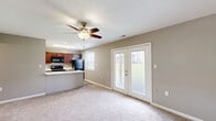 Located at 59 Port Ocall Dr in Indianapolis, Indiana, this two-bedroom, one-bathroom home offers a practical and well-organized single-floor layout. The combined kitchen and living area forms the heart of the home. The kitchen is outfitted with rich dark cabinetry, light countertops, black appliances including a refrigerator, electric range, and microwave, and a double-basin sink. Light wood-look flooring and a window with natural views add brightness to the space. The living room features plush carpeting, a ceiling fan, and a set of French doors that open to an outdoor view, filling the room with natural light. Both bedrooms are carpeted and include ceiling fans with light fixtures and windows overlooking the outdoors. The primary bedroom offers a closet for storage, while the second bedroom also includes closet access. A hallway connects the main living spaces to the bedrooms and the full bathroom, which features a clean white tub and shower combo, toilet, and warm wood-look tile flooring. Neutral warm-gray walls throughout the home create a cohesive and welcoming atmosphere, making the space move-in ready.