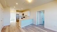 Located at 40 Pleasant St in Barnstable, MA, this single-floor unit offers a clean, modern design with a bright and functional layout. The open-concept living and kitchen area serves as the heart of the space, finished with light-toned luxury vinyl plank flooring that runs consistently throughout. The kitchen is well-appointed with white shaker-style cabinetry accented by matte black hardware, a full suite of stainless steel appliances including a refrigerator, electric range, and over-the-range microwave, and a peninsula that provides additional counter space and a natural dividing point between the kitchen and living area. The living area is airy and open, featuring recessed lighting, a wall-mounted mini-split heating and cooling unit, and a keyed entry door. Two bedrooms offer comfortable, sun-filled spaces, each with large windows that bring in natural light and overlook the surrounding neighborhood greenery. The bathroom is neatly finished with tile flooring and essential fixtures. Throughout the unit, warm neutral wall tones complement the light flooring, creating a cohesive and inviting atmosphere. This newly constructed space combines practical design with modern finishes, making it a well-suited residence in the heart of Cape Cod.