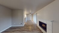This single-floor unit offers a thoughtfully laid-out living space with a clean, neutral color palette that creates a bright and welcoming atmosphere throughout. The main living area is generously sized, anchored by a tiled fireplace that serves as a focal point. Hardwood-style plank flooring runs throughout the main living and dining areas, adding warmth and continuity to the space. A ceiling fan with a light fixture provides both comfort and illumination.

The kitchen features white cabinetry, track lighting, a white appliance suite including a range and refrigerator, and a peninsula counter that opens to the dining and living areas — making it ideal for everyday living and entertaining. The layout allows for a natural flow between the kitchen, dining, and living spaces.

The bedrooms are carpeted and offer a quiet retreat, with one bedroom providing direct access to a bathroom equipped with white cabinetry and a vanity. The bathrooms are finished with clean, white fixtures, including a shower-tub combination, a single-basin vanity with a speckled countertop, and a large mirror.

Additional windows with blinds allow natural light to filter throughout the unit, contributing to the overall bright and airy feel of this well-maintained space.