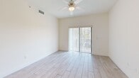 Located at 26710 SW 140th Ave in Homestead, FL, this 3-bedroom, 2-bathroom residence offers a bright, well-organized single-floor layout designed for comfortable living. Light-toned wood-look tile flooring runs throughout the home, creating a clean and cohesive aesthetic. The open-concept kitchen features white cabinetry, a peninsula with a built-in sink and countertop seating, stainless steel appliances including a refrigerator and range, and a skylight overhead that bathes the space in natural light. The kitchen flows seamlessly into the living area, which is equipped with a ceiling fan and sliding glass doors leading to a private balcony. In-unit laundry with a full-size washer and dryer is conveniently located just off the main living space. The three bedrooms are well-proportioned, each featuring ceiling fans, natural light from windows with vertical blinds, and generous closet space — five closets total are distributed throughout the unit. The primary bedroom includes a mirrored closet and direct outdoor views. Both bathrooms are finished with white vanities, matching tile flooring, and tub-shower combinations. The overall ambiance is light, airy, and move-in ready, reflecting a modern and functional design sensibility.