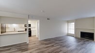 This single-story residence offers a well-organized layout with a neutral color palette and consistent finishes throughout. The living area is a standout space, anchored by a classic fireplace framed by two large windows that allow natural light to fill the room. Wood-look plank flooring extends through the main living and dining areas, adding warmth and visual continuity.

The kitchen is thoughtfully designed with white shaker-style cabinetry, white quartz countertops, a subway tile backsplash, a stainless steel sink, and black appliances including a refrigerator, range, and microwave. A peninsula counter connects the kitchen to the living area, creating an open, functional flow between spaces.

The bedrooms are carpeted and comfortably sized, with one featuring a walk-in closet and direct access to an outdoor area via a glass door. The primary bathroom includes a double-sink vanity with white countertops, a large mirror, and a glass-enclosed walk-in shower. A secondary bathroom offers a full tub-shower combination with wood-look flooring and a clean, efficient layout. Overall, the unit presents a modern yet understated aesthetic suitable for everyday living.