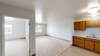 Located at 1220 Estes Park Ct in Rapid City, South Dakota, this one-bedroom, one-bathroom unit offers a practical and well-organized single-floor layout. The open living and dining area features neutral carpet, white walls, and a baseboard heating system, with a window that brings in natural light and views of the surrounding greenery. The kitchen is positioned adjacent to the living space and is outfitted with warm honey-toned wood cabinetry offering ample upper and lower storage, light countertops, a stainless steel sink, an electric range, and a full-size refrigerator. Tile flooring in the kitchen provides a durable, easy-to-clean surface that transitions seamlessly from the carpeted living area. The bedroom is a comfortable, carpeted space with a baseboard heater and a window fitted with blinds, offering a quiet retreat. A dedicated walk-in closet off the bedroom features full-width shelving and a hanging rod, providing generous storage. The bathroom includes a vanity with a sink, a toilet, and a towel bar, finished with light tile flooring. The overall layout is efficient and straightforward, making this a functional space well-suited for everyday living in Rapid City.