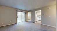 Located at 1905 W Appleway Ave in Coeur d'Alene, Idaho, this ground-floor unit offers a practical and comfortable single-level layout. The living area is finished with plush carpeting and features a sliding glass door fitted with vertical blinds, allowing natural light to fill the space while providing access to an outdoor area. A wall-mounted air conditioning unit and baseboard heating ensure year-round climate control throughout the unit.

The kitchen is bright and functional, showcasing white cabinetry, light-toned countertops, and a full suite of white appliances including a refrigerator, electric range, and overhead range hood. Light wood-style flooring runs through the kitchen, and a window overlooking the greenery outside adds a pleasant natural touch.

The bedrooms are carpeted and generously sized, each equipped with baseboard heating and windows that bring in natural light. Closet storage is provided via sliding-door closets with built-in shelving and hanging rods, offering practical organization solutions.

The bathroom is clean and straightforward, featuring a full tub and shower combination. Throughout the unit, neutral warm-beige walls and textured ceilings create a cohesive, understated aesthetic that provides a versatile backdrop for a variety of interior styles.