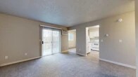 Located at 1905 W Appleway Ave in Coeur d'Alene, Idaho, this ground-floor unit offers a practical and comfortable single-level layout. The living area is finished with plush carpeting and features a sliding glass door fitted with vertical blinds, allowing natural light to fill the space while providing access to an outdoor area. A wall-mounted air conditioning unit and baseboard heating ensure year-round climate control throughout the unit.

The kitchen is bright and functional, showcasing white cabinetry, light-toned countertops, and a full suite of white appliances including a refrigerator, electric range, and overhead range hood. Light wood-style flooring runs through the kitchen, and a window overlooking the greenery outside adds a pleasant natural touch.

The bedrooms are carpeted and generously sized, each equipped with baseboard heating and windows that bring in natural light. Closet storage is provided via sliding-door closets with built-in shelving and hanging rods, offering practical organization solutions.

The bathroom is clean and straightforward, featuring a full tub and shower combination. Throughout the unit, neutral warm-beige walls and textured ceilings create a cohesive, understated aesthetic that provides a versatile backdrop for a variety of interior styles.