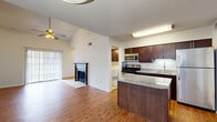 This efficient and thoughtfully designed single-floor residence offers a seamless blend of comfort and functionality. The open-concept kitchen and living room serves as the heart of the home, featuring rich dark-wood cabinetry, granite countertops, a breakfast bar island, and a full suite of stainless steel appliances including a refrigerator, range, microwave, and dishwasher. Wood-look flooring flows throughout the living spaces, adding warmth and continuity. The living room is highlighted by soaring vaulted ceilings, a ceiling fan, a classic wood-burning fireplace with a tiled hearth, and a sliding glass door that invites natural light and outdoor access. A dedicated laundry area is conveniently located just off the kitchen. The bedroom is a well-sized, bright retreat with a ceiling fan, a large window with outdoor views, and direct access to a closet. The bathroom features a full tub-shower combination with clean white tile and a decorative mosaic accent border. An entrance area completes the layout, offering a logical flow throughout the home. The textured ceilings and neutral wall tones throughout provide a versatile backdrop suited to a variety of interior styles.