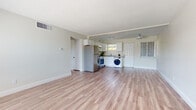 This single-floor unit offers a clean, functional layout designed for comfortable everyday living. Light-toned luxury vinyl plank flooring runs throughout the entire space, lending a cohesive and modern aesthetic to every room.

The open-concept living area is generously sized, with neutral-painted walls, a textured ceiling, and centrally located air vents ensuring consistent climate control. The space flows directly into the kitchen, which is well-appointed with white shaker-style cabinetry, granite-look countertops, and a full suite of stainless steel appliances including a refrigerator, electric range, and over-the-range microwave. A dedicated space within the kitchen accommodates an in-unit washer, adding everyday convenience. A window above the sink brings in natural light and garden views.

The unit includes at least two private rooms, each featuring windows fitted with horizontal blinds. One room overlooks lush outdoor greenery, offering a pleasant natural view. Both rooms are bright and adaptable for various uses.

The bathroom features wood-look vinyl flooring, a tiled shower-tub combination, a gray vanity with modern hardware, and a crisp, clean finish throughout.