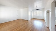 Located in Los Angeles' vibrant 90018 neighborhood, this one-bedroom, one-bathroom home offers a well-designed single-floor layout with a clean, modern aesthetic throughout. Rich hardwood floors flow continuously across the open living and dining area, which is bathed in natural light from large windows framing views of mature outdoor greenery. A sleek ceiling fan anchors the space, enhancing airflow and comfort.

The kitchen stands out as a highlight of the home, featuring crisp white shaker cabinetry with matte black hardware, striking marble-look quartz countertops and flooring, an undermount stainless steel sink with a black gooseneck faucet, a gas range, and a stainless steel refrigerator. A window above the sink brings in additional natural light, making the space feel bright and airy.

The spacious bedroom includes corner windows that flood the room with daylight, a ceiling fan, and an impressively large built-in white cabinetry wall unit offering generous storage. Three closets throughout the home provide ample organizational space.

The bathroom features a full tub-shower combination with white tile surround and matte black fixtures, maintaining the home's consistent modern design language. A hallway connects all areas of the home efficiently, completing this thoughtfully laid-out residence.