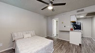 Located at 4815 E Thomas Rd in Phoenix, AZ, this efficient one-bedroom, one-bathroom unit is thoughtfully designed to maximize every inch of its compact footprint. The layout flows across a single floor, offering a cohesive and easy-to-navigate living space.

The spacious bedroom serves as the heart of the unit, featuring durable wood-look plank flooring, neutral gray walls, and a ceiling fan with integrated lighting — a practical touch well-suited to Arizona's warm climate. A window with blinds allows for natural light and ventilation, while a door leads directly to the bathroom, adding convenience. The bedroom also connects to a small built-in countertop area that transitions into the kitchen space.

The kitchen is equipped with stainless steel appliances, including an electric range with oven, an over-the-range microwave, and a full-size refrigerator. White cabinetry and matching wood-look flooring tie the kitchen aesthetically to the rest of the unit.

The bathroom is modern and clean, showcasing a floating wood-toned vanity with a white undermount sink, brushed nickel fixtures, a framed mirror, and stylish vanity lighting. The textured ceiling is consistent throughout the unit, adding a classic architectural touch. Overall, the space presents a clean, updated aesthetic suitable for efficient single-occupant living.