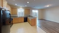 This well-appointed two-story home offers 3 bedrooms and 2.5 bathrooms across a thoughtfully designed layout. The main level features an open-concept living and kitchen area, where warm wood-look plank flooring flows through the living space and transitions to tile in the kitchen. The kitchen is equipped with light maple cabinetry, granite-look countertops, a peninsula with bar seating, black appliances including a refrigerator, stove, microwave, and dishwasher, and recessed lighting throughout. A sliding glass door provides access to the outdoor area, filling the kitchen with natural light. A convenient half bathroom is also located on the main floor. A white-railed staircase leads to the upper level, where all three bedrooms are situated. The carpeted bedrooms are bright and generously sized, with multiple windows allowing ample natural light. The primary suite includes double-door entry, a spacious walk-in closet with built-in shelving, and an en-suite bathroom featuring a dual-sink vanity with light wood cabinetry, a walk-in glass shower, a separate soaking tub, and wood-look flooring. Additional bathrooms feature light wood vanities and wood-look flooring, maintaining a consistent, clean aesthetic throughout the home.