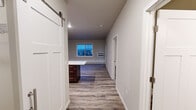 Located in Cedar Rapids, Iowa, this single-floor unit offers a thoughtfully designed layout with modern finishes throughout. The kitchen serves as a central highlight, featuring rich dark-stained cabinetry, stainless steel appliances including a refrigerator, range, microwave, and dishwasher, a double-basin sink, and a large island with a crisp white countertop — ideal for both meal preparation and casual dining. Wood-style luxury vinyl plank flooring runs throughout the main living and kitchen areas, providing a clean and durable foundation.

The living area is generously sized with large windows that allow natural light to fill the space, complemented by a wall-mounted HVAC unit and baseboard heating. A private exterior door leads to an outdoor deck area, adding a functional outdoor element to the unit. The bedrooms are finished with plush carpet, large windows with blinds, and baseboard heating, creating comfortable and quiet retreats.

The bathroom is outfitted with a wide vanity featuring dark cabinetry, white countertops, and a large mirror, alongside a tall storage tower for added organization. A stylish sliding barn door connects to a dedicated laundry area, which includes a full-size washer and dryer and wire shelving for storage. The overall aesthetic is clean, contemporary, and functional throughout.