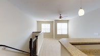 This thoughtfully designed single-floor residence offers a comfortable and functional layout with a clean, neutral aesthetic throughout. The open living area is bright and welcoming, featuring plush carpeting, warm beige walls, and multiple windows that invite an abundance of natural light. A ceiling fan with an integrated light fixture adds both practicality and a subtle decorative touch. A dark-wood staircase railing frames the space elegantly, adding a rich contrast to the light-toned surroundings.

The kitchen is well-equipped for everyday cooking, showcasing rich dark-espresso cabinetry, granite-style countertops, and a full suite of stainless steel appliances, including a refrigerator, electric range, and built-in microwave. Stone-look tile flooring ties the space together with a durable, stylish finish.

The bedroom is a serene and carpeted retreat, bathed in soft natural light from a window with blinds, offering a quiet and restful atmosphere.

The bathroom is efficiently laid out and features dark-stained cabinetry, a single vanity with a light countertop, an illuminated mirror, tile flooring, and a bathtub-shower combination — all finished in a cohesive, contemporary style. Throughout the space, consistent use of dark cabinetry and neutral tones creates a harmonious and modern feel.