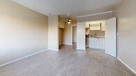 Located at 12235–12245 Alondra Blvd in Norwalk, California, this single-floor unit offers a practical and efficiently designed layout. Light-toned, wood-look flooring runs consistently throughout the space, contributing to a clean and cohesive aesthetic.

The combined living and dining area serves as the heart of the unit. It features warm beige walls, a textured ceiling, and a ceiling fan that aids in air circulation. A wall-mounted HVAC unit provides climate control, and a window allows natural light to enter while offering a view to the exterior. A wall-mounted heater vent is also present, adding functional versatility.

The kitchen is semi-enclosed and accessible directly from the main living area. It includes white cabinetry both above and below the countertop, a sink, and space for essential appliances, including a full-size refrigerator. The layout is straightforward and makes efficient use of the available space.

The bathroom is well-appointed with white cabinetry, an over-toilet storage unit, a single-sink vanity with a mirror, and a full shower-tub combination. A window above the tub provides natural ventilation and light.

Two closets provide dedicated storage solutions within the unit. The overall design prioritizes functionality, with neutral finishes and durable materials that create a clean, move-in-ready environment.