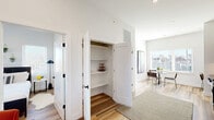 Located at 220 N Walton Blvd in Bentonville, AR, this thoughtfully designed one-bedroom, one-bathroom residence offers a clean, contemporary aesthetic across a single floor. Light hardwood-style flooring runs throughout, complementing crisp white walls and modern black hardware accents that create a cohesive, minimalist feel.

The open-concept kitchen and dining area is well-appointed with flat-front cabinetry in a warm natural wood tone, dark countertops, a white subway tile backsplash, and stainless steel appliances including a range, microwave, and dishwasher. A compact dining nook with a window overlooks the outdoors, filling the space with natural light.

The living room features elevated ceilings, multiple windows, and a glass-paned exterior door that floods the room with daylight and provides outdoor access. A hallway with a built-in storage closet featuring multiple shelves adds practical organization to the layout.

The bedroom is bright and airy, benefiting from corner windows on two walls that invite ample natural light. The bathroom is finished with wood-toned cabinetry, dark countertops, and a sleek tub-shower combination accented by vertical white tile and matte black fixtures. Throughout the residence, the design balances modern style with functional, efficient use of space.
