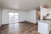 This well-appointed single-floor unit offers a clean, modern aesthetic with consistent light-toned laminate flooring and crisp white walls throughout. The open-concept living area is filled with natural light from a large sliding glass door that opens to a private balcony, providing outdoor views and a bright, airy atmosphere. A textured ceiling adds character to the living space, which flows seamlessly into the kitchen via a peninsula counter with granite-style laminate surfaces.

The galley-style kitchen is efficiently designed with ample white cabinetry, granite-look countertops, stainless steel appliances including a refrigerator and electric range, and a stainless steel sink — offering both functionality and a contemporary feel.

The bedrooms are generously sized, each featuring large windows that invite natural light and warm wood-toned doors that complement the flooring. The unit includes two full bathrooms: one featuring a tub/shower combo with a white surround and a vanity with white cabinetry, and the other offering a spacious layout with a wide vanity and grab bars.

A dedicated in-unit laundry area houses a full-size top-loading washer and dryer along with overhead wire shelving, adding everyday convenience. The layout, as reflected in the floorplan, is thoughtfully organized for efficient use of space.
