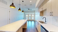 Located at 550 Great Circle Rd in Nashville, TN, this well-appointed one-bedroom, one-bathroom unit offers a thoughtfully designed single-level layout with modern finishes throughout. The open-concept living area seamlessly integrates the kitchen, dining, and living spaces, creating an airy and functional environment. Rich hardwood-style flooring runs throughout, complementing the clean, contemporary aesthetic.

The kitchen is a standout feature, showcasing light wood cabinetry with black hardware, quartz countertops, a subway tile backsplash, and a full suite of stainless steel appliances including a refrigerator, range, microwave, and dishwasher. A large kitchen island with built-in shelving and pendant lighting above serves as both a prep space and a casual dining focal point. French doors at the end of the living area open to a private balcony, filling the space with natural light.

The bedroom is bright and comfortable, featuring two windows with outdoor views and direct access to a spacious walk-in closet with built-in shelving. The bathroom offers a clean, classic design with subway tile surrounding a full soaking tub and shower combination, accented by matte black fixtures. Additional conveniences include a dedicated laundry area, utility room, and entrance foyer, rounding out this efficient and stylish Nashville residence.