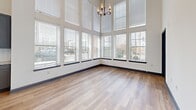 This contemporary 710 square foot apartment in Richmond, VA, showcases an impressive open-concept design. The space is defined by its soaring ceilings and wall of windows, creating an expansive, light-filled atmosphere. The living area boasts hardwood flooring and is illuminated by a stylish chandelier, complementing the abundance of natural light.

The gourmet kitchen is a standout feature, equipped with stainless steel appliances, including a side-by-side refrigerator and built-in microwave. Gray cabinetry contrasts beautifully with white subway tile backsplash, while a large center island with a granite countertop provides additional workspace and casual dining options.

Large windows with white blinds offer picturesque city views and flood the space with natural light. The apartment's layout maximizes the use of its 710 square feet, creating a sense of spaciousness and flow between the kitchen and living areas. A closet provides essential storage space, ensuring a clutter-free environment.

The property's location at 500 W 14th St places residents in the heart of Richmond, offering urban convenience coupled with a modern, luxurious living space. This single-floor apartment seamlessly blends functionality with style, making it an ideal home for those seeking a contemporary urban lifestyle.