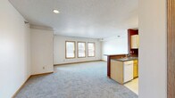 Located at 420 Main Ave in Moorhead, MN, this 2-bedroom, 1-bathroom unit offers a comfortable and functional single-floor layout. The open-concept living and kitchen area serves as the heart of the home, featuring a spacious carpeted living room bathed in natural light from a trio of wood-trimmed windows. The adjacent kitchen is well-equipped with ample honey-toned cabinetry, laminate countertops, a stainless steel sink, and white appliances including a range, over-the-range microwave, dishwasher, and refrigerator. Bold accent walls in deep red add a touch of character to the kitchen space.

The two carpeted bedrooms are quiet and comfortable, each offering closet storage and warm wood-trimmed accents. The primary bedroom provides a generous footprint with natural light from a window overlooking the surrounding area. The full bathroom features tile flooring, a single-sink vanity with wood cabinetry, and a large mirror. A dedicated utility room adds practical storage and functionality. The unit also includes a private balcony accessible via a glass-paneled door, offering outdoor views of the Moorhead streetscape — a pleasant extension of the living space.