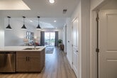 Located at 315 SW Pine Island Rd in Cape Coral, Florida, this well-appointed one-bedroom, one-bathroom unit offers a thoughtfully designed single-floor layout with modern finishes throughout. Light-toned hardwood-style flooring flows seamlessly across the entire space, contributing to a cohesive and airy feel.

The open-concept kitchen and living area serves as the heart of the unit. The kitchen is outfitted with warm-toned shaker cabinetry, crisp white countertops, stainless steel appliances including a range, over-the-range microwave, refrigerator, and dishwasher, complemented by a geometric tile backsplash and sleek matte black hardware. Pendant lighting over the counter adds a contemporary touch, while a tray ceiling detail elevates the space.

The living room is bright and welcoming, featuring recessed lighting, a sliding glass door that opens to a private balcony with outdoor views, and ample room for comfortable seating.

The spacious primary bedroom features a tray ceiling, a ceiling fan, and a large window that allows natural light to fill the room. The full bathroom includes a wide vanity with wood cabinetry, white countertop, and a glass-enclosed walk-in shower.

A dedicated laundry area with a full-size washer and dryer and a closet with wire shelving complete this efficiently designed unit.