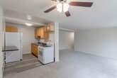 This single-floor unit offers a practical and well-organized layout designed for comfortable everyday living. The open-concept living and dining area is generously proportioned, featuring soft neutral carpeting, warm beige walls, and a ceiling fan with a light fixture that adds both functionality and a welcoming feel. Large sliding glass doors along one wall flood the space with natural light and provide views of the surrounding greenery, while vertical blinds allow for easy light control.

The kitchen is positioned adjacent to the living area and is equipped with warm honey-toned wood cabinetry, dark countertops, a gas range, a refrigerator, and a sink — offering ample storage and workspace for cooking. The kitchen transitions seamlessly into the living area via an open pass-through design, making the space feel connected and social. Wood-look flooring in the kitchen contrasts cleanly with the carpeted living areas.

The bedrooms are spacious and carpeted, each featuring windows with outdoor views and an abundance of built-in closet storage, including multiple closets with shelving and hanging rods. The bathroom is finished with white subway tile wainscoting, a white vanity with an overhead mirror, overhead lighting, and wood-look flooring, creating a clean and bright atmosphere throughout.