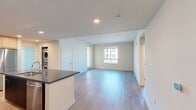 Located in Riverside, CA, this North Grove apartment offers 860 square feet of contemporary single-floor living across 3 bedrooms and 2 bathrooms. The modern kitchen is a standout feature, showcasing two-tone cabinetry with dark lower and white upper cabinets, sleek quartz countertops, a subway tile backsplash, and stainless steel appliances including a refrigerator, range, and built-in microwave. Light wood-style flooring runs throughout the kitchen and living areas, creating a clean, cohesive aesthetic. The open layout connects the kitchen to the living room, maximizing the use of space. The primary bedroom spans 130 square feet and features plush carpeting, and other bedrooms also offer carpet flooring with large windows that invite abundant natural light and views of the surrounding community. Both bathrooms are finished with light wood-style flooring, tiled shower-tub combinations, and dark-toned vanities. A hallway and closet provide practical storage solutions. The unit also features a private outdoor view overlooking the community's solar-covered parking area. The overall design emphasizes clean lines, neutral tones, and modern finishes throughout.