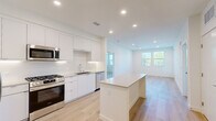 Located at 6535 Alvarado Road in San Diego, CA, this modern 2-bedroom, 2-bathroom residence offers a thoughtfully designed single-floor layout. The open-concept kitchen and living area serves as the heart of the home, featuring sleek white cabinetry extending to the ceiling, a crisp tile backsplash, stainless steel appliances including a gas range, built-in microwave, dishwasher, and refrigerator, and a central island with a light countertop — ideal for dining or entertaining. Light wood flooring flows seamlessly throughout the entire residence, complementing the bright, white walls and recessed lighting that create a clean, contemporary ambiance. Natural light fills the living area through multiple windows with views of the surrounding greenery. Both bedrooms are well-proportioned and bright, each featuring windows with blinds. The spacious primary bedroom includes direct access to a dedicated bathroom and a walk-in closet outfitted with built-in shelving and hanging rods. The primary bathroom features a glass-enclosed shower, a long white vanity, and wood-look flooring. The second bathroom offers a soaking tub with marble-style tile surround and a built-in niche. A dedicated closet provides additional storage.