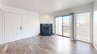 Located at 12050 Candelaria Rd NE in Albuquerque, NM, this well-appointed one-bedroom, two-bathroom unit offers a thoughtfully designed single-floor layout. The open-concept living, dining, and kitchen area serves as the heart of the home, finished with durable wood-look flooring throughout and bright white walls that maximize natural light. A striking dark-tiled corner fireplace anchors the living space, while a sliding glass door leads to a private balcony, offering outdoor views of the surrounding neighborhood. The kitchen is equipped with stainless steel appliances, including a full-size refrigerator, and features a window with shutters that brings in additional natural light. The bedroom is a comfortable retreat, complete with a ceiling fan, double closet doors providing ample storage, and matching wood-look flooring. Both bathrooms are clean and well-finished — one features a dual-sink vanity with dark countertops, white cabinetry, black hardware, framed mirrors, and wood-look flooring, while the other includes a tub-shower combination with white subway tile surround. Additional spaces include a hallway, a dedicated closet, and a utility room, rounding out the functional and efficient layout of this Albuquerque residence.