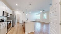 Located in Spring Hill, TN, this thoughtfully designed single-floor residence offers a bright and modern living experience. The open-concept kitchen and living area serves as the heart of the home, anchored by a large central island with granite countertops and a built-in sink, illuminated by stylish pendant lighting. The kitchen is equipped with stainless steel appliances, including a range, microwave, and refrigerator, complemented by white upper cabinetry and gray lower cabinets. Light hardwood-style flooring flows seamlessly throughout the entire space, enhancing the clean, cohesive aesthetic. The spacious living room is bathed in natural light from multiple windows with views of lush greenery, and features a ceiling fan and recessed lighting. The bedroom is a comfortable retreat with its own large window framing outdoor greenery, a ceiling fan, and direct access to a dedicated closet. The full bathroom features a granite-topped vanity with ample cabinet storage and a large mirror. A separate laundry room houses a full-size washer and dryer alongside a water heater. The overall ambiance is crisp, modern, and move-in ready, ideal for those seeking a low-maintenance lifestyle in a well-appointed space.