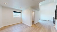 Located at 1047 Fedora Street in Los Angeles, this modern two-story unit offers a well-designed layout spread across two levels. The main floor is generously proportioned, anchored by an open living area with light-toned hardwood flooring that flows throughout the space. The kitchen is outfitted with warm wood cabinetry, stainless steel appliances including a range, dishwasher, and refrigerator, and clean white countertops. A sleek staircase with a contemporary metal railing leads to the upper level. Soaring ceilings on the main floor lend an airy, open feel, while recessed lighting and a large sliding glass door flood the space with natural light and provide direct access to a private balcony with views of the surrounding neighborhood. The upper level offers a more intimate space, featuring the same hardwood flooring and a window with a roller shade that frames exterior views. Rich wood-paneled double doors add a refined, architectural touch. The bathroom is well-appointed with a modern floating vanity, warm wood cabinetry, a framed mirror, mosaic tile flooring, and a walk-in shower with herringbone tile walls. Clean white walls and crisp trim throughout create a bright, cohesive aesthetic across the entire unit.