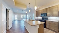 Located at 1000 Oak Street in Reynoldsburg, Ohio, this two-story home offers a thoughtfully designed layout with modern finishes throughout. The heart of the home is an open-concept kitchen and living area, where soaring vaulted ceilings create an impressive sense of volume and openness. The kitchen is well-appointed with rich wood cabinetry, a large center island featuring a double-basin sink and pendant lighting overhead, light-toned countertops, and black appliances including a range, microwave, and refrigerator. Wood-look flooring extends throughout the main living areas, lending warmth and continuity to the space.

The living area flows naturally from the kitchen, bathed in natural light from multiple windows and finished with a ceiling fan for added comfort. Bedrooms are carpeted and generously sized, each with windows that bring in outdoor views and natural light. The bathrooms feature wood-style flooring, warm cabinetry with granite-style countertops, and clean, neutral finishes.

Completing the home is a spacious attached two-car garage with a concrete floor and automatic door opener, providing ample storage and convenient direct access. The overall aesthetic is clean, contemporary, and move-in ready.