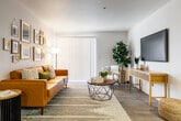 This single-floor residence offers a thoughtfully designed open-concept layout that seamlessly connects the main living areas. The kitchen is outfitted with gray shaker-style cabinetry, white quartz countertops, a subway tile backsplash, and a full suite of stainless steel appliances including a refrigerator, electric range, microwave, and dishwasher. A galley-style configuration maximizes efficiency, while a peninsula with additional counter space opens directly to the dining area and living room. The living room is generously proportioned, featuring wood-look flooring, a sliding glass door that allows natural light to fill the space, and a dedicated media wall. A hallway connects the living areas to the private rooms, including a carpeted bedroom with a large window and ample wall space. A versatile secondary room with carpet flooring serves well as a home office or creative studio. Two bathrooms are present: one featuring hexagonal tile flooring, a vanity with gray cabinetry, and a tub-shower combination, and another with wood-look tile flooring and a wide vanity. Throughout, clean white walls, recessed lighting, and cohesive warm-toned décor create a bright, welcoming atmosphere that balances comfort with modern functionality.