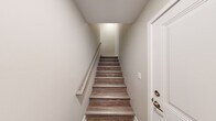 Located at 873 Westbury Blvd in Howell, MI, this two-story home offers a thoughtfully designed layout across two floors. Entry is made through a clean, narrow foyer featuring wood-look flooring and a staircase with a sleek metal handrail leading to the main living level above. The primary floor hosts the bulk of the living space, including a bright living room with wood-look plank flooring and recessed lighting, creating a warm and open atmosphere. The galley-style kitchen is outfitted with white shaker cabinetry, white quartz countertops, stainless steel appliances including a refrigerator and range, and a built-in microwave — all set against light hardwood-style floors. Two carpeted bedrooms provide comfortable retreats, with the primary bedroom offering generous proportions and a dedicated closet. Both bathrooms are finished with white vanities, wood-look flooring, and clean, neutral tones. A dedicated laundry room accommodates a full-size washer and dryer. The attached garage offers direct interior access and overlooks the residential neighborhood. Neutral wall tones and consistent flooring choices throughout lend the home a cohesive and move-in-ready feel.