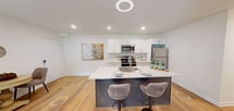 Located at 277 N Rose, Unit 102 in Mount Clemens, MI, this 790-square-foot, single-floor apartment features 1 bedroom, 1 bathroom, a dedicated office, and in-unit laundry. The open-concept kitchen and living area is anchored by a modern kitchen boasting white shaker cabinetry with gold hardware, quartz countertops, a two-toned island with a built-in sink, and stainless steel appliances including a range, microwave, and full-size refrigerator. Light wood-style flooring flows throughout the main living areas. The living room is bright and airy, featuring a sliding glass door that allows natural light to fill the space. A dedicated dining nook adjoins the living area for convenient everyday use. The 120-square-foot bedroom offers a sliding-door closet, natural light from a window, and durable flooring. The office provides a quiet, flexible space suitable for work or study. The full bathroom features marble-style tile flooring, a white vanity with gold hardware, built-in open shelving, and a tub-shower combination. A separate laundry room houses a full-size washer and dryer alongside the water heater, adding practical convenience to this well-appointed apartment.