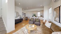 Located at 566 S Redwood Rd in Salt Lake City, Utah, this contemporary three-story townhome offers a well-designed layout across three distinct floors. The ground level features a welcoming entrance with French doors that invite natural light, along with a flex room enclosed in glass — ideal as a home office or study — plus a dedicated laundry room and utility space.

The main living floor showcases a bright, open-concept great room that seamlessly unites the living, dining, and kitchen areas. The kitchen is appointed with crisp white cabinetry, quartz countertops, stainless steel appliances, a center island with bar seating, and warm hardwood-style flooring. The adjoining living area is bathed in natural light from multiple windows and features a wall-mounted mini-split system for efficient climate control.

The upper floor houses all three bedrooms, each with dedicated closets. The generously sized primary bedroom benefits from dual windows and its own mini-split unit, creating a comfortable private retreat. The shared full bathroom includes a tub-shower combination and wood-look flooring.

A slatted wood privacy fence encloses an outdoor ground-level area, providing a functional exterior space. The home's modern exterior features bold dark siding, completing its clean, contemporary aesthetic.