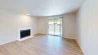 Located in Tacoma, WA, this thoughtfully updated 3-bedroom, 2-bathroom unit offers a clean, modern aesthetic across a well-organized single-floor layout. The bright living room serves as the heart of the home, featuring light luxury vinyl plank flooring, a sleek fireplace, and a sliding glass door that opens to a private balcony with outdoor views — filling the space with natural light. The kitchen is well-appointed with white shaker cabinetry, quartz countertops with subtle veining, a stainless steel refrigerator, electric range with overhead ventilation hood, and a dishwasher — all set against matching light wood-tone flooring. The primary bathroom impresses with a dual-sink vanity topped in elegant quartz, white cabinetry with brushed nickel hardware, and a window for natural light. The bedrooms offer a comfortable, neutral palette — the secondary bedrooms feature plush carpet and closet space, providing a cozy retreat. A dedicated laundry area houses a full-size GE washer and dryer, adding everyday convenience. Throughout the unit, a consistent use of white walls, light flooring, and brushed nickel fixtures creates a cohesive and contemporary living environment.