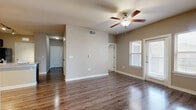 Located along US Highway 281 N in San Antonio, Texas, this single-story 2-bedroom, 2-bathroom home offers a well-designed layout with a comfortable, functional floor plan. The open living area features rich hardwood-style flooring, a ceiling fan with light fixture, and neutral warm-toned walls that create a bright and welcoming atmosphere. Natural light flows in through multiple windows adorned with blinds, and a door provides direct access to one of two outdoor balconies. The kitchen is a standout feature, boasting dark espresso cabinetry, granite countertops, a large peninsula island with an undermount sink, and black appliances including a range, microwave, and refrigerator. Track lighting overhead adds a modern touch, and a pantry provides additional storage. Both bedrooms are carpeted and equipped with ceiling fans, offering a cozy retreat. The spacious primary bedroom includes direct access to an en-suite bathroom and a generous walk-in closet with wire shelving. The bathrooms feature granite-topped dark vanities and hardwood-style flooring, with one showcasing a full soaking tub and tiled surround. Additional highlights include a dedicated laundry area and three closets throughout for excellent storage capacity.