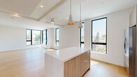 Located at 1257 N Detroit St in the heart of West Hollywood, this contemporary two-story residence offers three bedrooms, three bathrooms, and a thoughtfully designed open-concept layout spread across two floors. The main level is anchored by a sleek kitchen and living area featuring vaulted ceilings, light oak hardwood flooring, and floor-to-ceiling black-framed windows that flood the space with natural light. The kitchen is outfitted with crisp white upper cabinetry, warm wood-toned lower cabinets, a striking quartz waterfall island, stainless steel appliances, and stylish pendant lighting. A private balcony extends from the main level, offering panoramic views of the West Hollywood skyline and surrounding neighborhood under sunny California skies. The bedrooms are bright and airy, each benefiting from large black-framed windows that frame outdoor views and continue the modern aesthetic. Closets with sleek mirrored sliding doors provide ample storage. The bathrooms are finished with warm wood vanities, clean white countertops, and light tile flooring, maintaining a cohesive and refined palette throughout. A connecting staircase leads to the upper level, which provides additional bedroom space. The overall ambiance is clean, modern, and luminous — a polished residence designed for contemporary West Hollywood living.