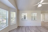 Located in The Woodlands, TX, this single-floor, three-bedroom, two-bathroom home offers a thoughtfully designed layout with a blend of comfort and functionality. The living room is a standout space, featuring soaring vaulted ceilings, a ceiling fan, and a charming bay window that floods the room with natural light and offers views of the surrounding greenery. Light-toned hardwood-style flooring extends through the main living areas, complementing the home's bright, neutral color palette throughout.

The kitchen is efficiently designed with a pass-through counter that connects it to the living area, wood-accented cabinetry, a stainless steel refrigerator, and a range — making it both practical and open. A hallway connects the main areas to the private quarters of the home.

The primary bedroom is generously sized, featuring plush carpeting and dedicated closet space. The two additional bedrooms also feature carpet flooring and windows that allow natural light to fill each room. Both bathrooms are finished with granite-style countertops and tiled shower-tub combinations, providing a clean and functional design. The home's consistent use of warm neutral tones and natural light throughout creates a welcoming and cohesive ambiance.