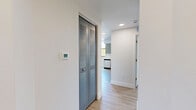 Located in Miami, FL, this thoughtfully designed 3-bedroom, 2-bathroom home on a single floor delivers a clean, contemporary aesthetic throughout. Light wood-style flooring flows seamlessly across the living areas, hallways, and bedrooms, lending warmth and cohesion to the space. The modern kitchen is a standout feature, outfitted with sleek gray cabinetry, white countertops, a full suite of stainless steel appliances including a refrigerator, range, microwave, and dishwasher, and a window framing lush green views. The open layout connects the kitchen to the living area, creating an airy, functional environment. Two well-appointed bathrooms complement the home — one features a tiled tub-shower combo with chrome fixtures and a blue-gray vanity, while the second offers a walk-in tiled shower, a large mirror, and a matching vanity. The generously sized primary bedroom includes direct access to an en-suite bathroom. A dedicated walk-in closet with wire shelving provides ample storage. Two connecting hallways guide circulation throughout the home, and a louvered bifold closet door adds a practical design touch. A private outdoor balcony with bold steel columns offers open-sky views of the surrounding Miami neighborhood, completing this move-in-ready residence.