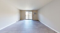 This 2-bedroom, 1-bathroom residence in Menomonee Falls, Wisconsin, offers a thoughtfully laid-out single-floor plan designed for comfortable everyday living. The open living room is a highlight of the space, featuring large-format tile flooring in a soft gray tone, a sliding glass door that opens to a private balcony, and a wall-mounted air conditioning unit, all bathed in natural light from the surrounding windows. The kitchen flows directly from the living area and showcases warm honey-toned cabinetry, white countertops, a classic subway tile backsplash, recessed lighting, and white appliances including a range, microwave, and refrigerator. Both bedrooms continue the tile flooring and neutral wall palette, with windows that bring in outdoor views of the surrounding neighborhood. The primary bedroom is generously sized and includes a sliding-door closet, while an additional dedicated closet space features built-in wire shelving for ample storage. The full bathroom is clean and functional, offering a tub-shower combination, a warm wood-toned vanity with a white countertop, and tile flooring. A hallway connects all areas of the home, completing this well-organized and move-in-ready layout.