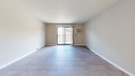 This 2-bedroom, 1-bathroom residence in Menomonee Falls, Wisconsin, offers a thoughtfully laid-out single-floor plan designed for comfortable everyday living. The open living room is a highlight of the space, featuring large-format tile flooring in a soft gray tone, a sliding glass door that opens to a private balcony, and a wall-mounted air conditioning unit, all bathed in natural light from the surrounding windows. The kitchen flows directly from the living area and showcases warm honey-toned cabinetry, white countertops, a classic subway tile backsplash, recessed lighting, and white appliances including a range, microwave, and refrigerator. Both bedrooms continue the tile flooring and neutral wall palette, with windows that bring in outdoor views of the surrounding neighborhood. The primary bedroom is generously sized and includes a sliding-door closet, while an additional dedicated closet space features built-in wire shelving for ample storage. The full bathroom is clean and functional, offering a tub-shower combination, a warm wood-toned vanity with a white countertop, and tile flooring. A hallway connects all areas of the home, completing this well-organized and move-in-ready layout.