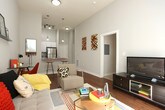 This single-story residence showcases a thoughtfully designed layout with modern finishes and functional living spaces. The living room serves as the heart of the home, featuring warm hardwood flooring, elevated ceilings with a ceiling fan, and a wall-mounted display shelf. A sliding glass door floods the space with natural light and provides direct outdoor access, while a dedicated nook accommodates a workspace.

The kitchen is outfitted with crisp white cabinetry extending to the ceiling, granite-style countertops, and a full suite of stainless steel appliances, including a range, microwave, dishwasher, and refrigerator. Light tile flooring completes the clean, bright aesthetic. An entryway adjoins the kitchen, offering a welcoming transition into the home.

The bedrooms are carpeted for comfort and feature tall ceilings with generous natural light. Each room offers ample wall space suitable for storage and décor. A utility area connects directly to a full bathroom and includes wire shelving for organization alongside a full-size washer and dryer, providing added convenience. The neutral color palette and consistent design language throughout the residence create a cohesive and comfortable living environment.