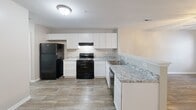 Located at 3430 Broad River Rd in Columbia, SC, this single-floor, 2-bedroom, 2-bathroom home offers a practical and well-appointed layout. The kitchen is a standout feature, showcasing crisp white shaker cabinets extending to the ceiling, light granite countertops, a tile-style floor, and black appliances including a refrigerator, electric range, and dishwasher. A built-in range hood and double-basin sink complete the functional space.

Both bedrooms are finished with plush carpeting and ceiling fans with integrated light fixtures, lending a comfortable, lived-in feel. Natural light filters in through windows framed with blinds, offering views of surrounding greenery. The primary bedroom includes a walk-in closet with built-in shelving, while the second bedroom features a double-door closet, providing ample storage.

The two bathrooms are clean and modern in style. One features a white vanity with granite countertop, a lighted mirror, and wood-look flooring. The second bathroom mirrors this aesthetic with the addition of a full tub-shower combination. Neutral wall tones and consistent flooring throughout the home create a cohesive and move-in-ready atmosphere well-suited for comfortable everyday living.